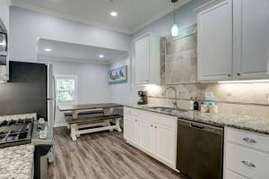 uma cozinha com armários brancos, um lavatório e um fogão em Renovated Beach Bungalow! em Galveston