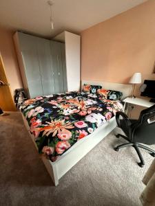 a bedroom with a bed with a floral comforter and a desk at Repton house in Woodford