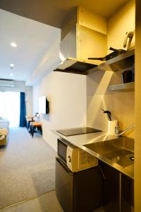 une cuisine avec un évier et un canapé dans une chambre dans l'établissement Apartment Hotel 11 Namba Minami Shin-Imamiya, à Osaka