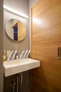 La salle de bains est pourvue d'un lavabo blanc et d'un miroir. dans l'établissement Apartment Hotel 11 Namba Minami Shin-Imamiya, à Osaka