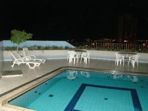a swimming pool with tables and chairs and a table and chairs at Rios Hotel in Rondonópolis
