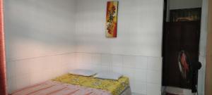 a small room with a yellow mattress on a white wall at Dharma homestay in Padangbai