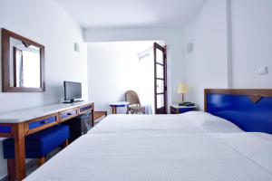 a bedroom with two beds and a desk and a mirror at Kalidon beach Hotel in Kokkari