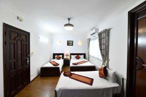 a room with two beds and a door at Phoenix Legend Hotel in Hanoi