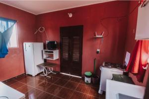 une cuisine avec des murs rouges et une porte noire dans l'établissement Sobrado do Eduardo, à Barra Grande
