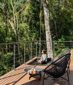 una mujer sentada en una terraza de madera con una silla en Refúgio Galli, en Encantado