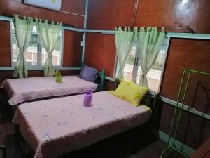 two twin beds in a room with curtains at Lungmin homestay in Mae Hong Son