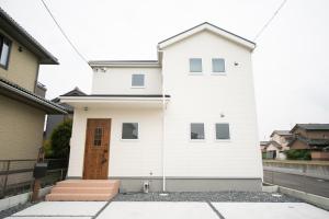 Hakuro的住宿－Nagashima Riverside Condominium，白色的房子,设有木门