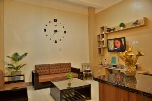 a living room with a couch and a clock on the wall at Umah Karet Homestay in Magelang