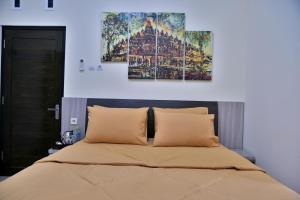 Umah Karet Homestay في ماغيلانغْ: غرفة نوم مع سرير مع لوحتين على الحائط