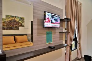 Umah Karet Homestay في ماغيلانغْ: غرفة معيشة مع أريكة وتلفزيون على الحائط