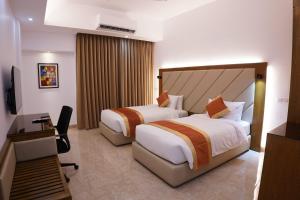 Cette chambre comprend deux lits et une télévision. dans l'établissement HOTEL STUDiO23, à Dhaka