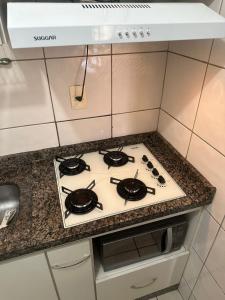 a stove top oven in a kitchen next to a counter at Thermas Paradise Cobertura 2 suítes e churrasqueira in Rio Quente