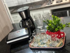 a tray of glasses sitting on a counter with a coffee maker at Thermas Paradise Cobertura 2 suítes e churrasqueira in Rio Quente