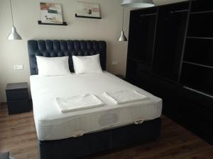 a bed with a black headboard and white sheets and pillows at Draga Apartment in Nesebar