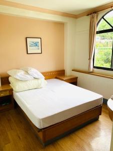 1 dormitorio con 1 cama con sábanas blancas y ventana en Yong Li Hotel, en Gukeng