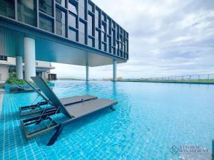 - une piscine avec un fauteuil en face d'un bâtiment dans l'établissement Bali Residences Sea View Suites Melaka, à Malacca