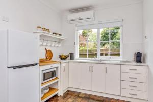 een witte keuken met een wastafel en een raam bij Hahndorf Creek Retreat - Unit 2 in Hahndorf