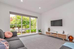 ein Wohnzimmer mit einem Sofa und einem TV in der Unterkunft Hahndorf Creek Retreat - Unit 2 in Hahndorf