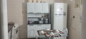 a kitchen with a refrigerator and a table in it at Melhor da Praia do Morro Apartamento até 10 pessoas in Guarapari