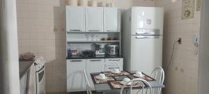 a kitchen with a refrigerator and a table in it at Conforto & Pé na Areia na Praia do Morro - Espaço Perfeito para Família e Amigos in Guarapari