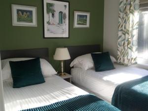 two beds in a room with green walls at Lodge in beautiful Kent countryside with fine views in Brookland