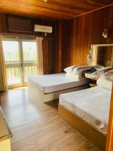 two beds in a room with wooden walls at Yong Li Hotel in Gukeng