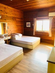 two beds in a room with wooden walls and a window at Yong Li Hotel in Gukeng