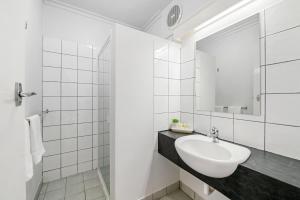 Baño blanco con lavabo y espejo en Coach House Launceston en Launceston