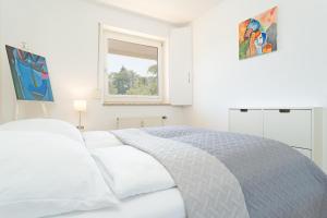 a white bedroom with a bed and a window at Haus Dieksee Holm Seeromantik in Malente