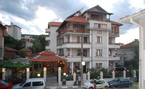 a large white building with cars parked in front of it at Guest House Lazur in Obzor
