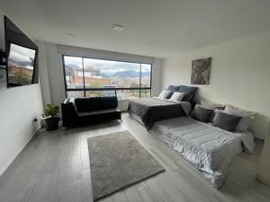 a living room with a couch and a bed and a window at Hermoso apartamento con terraza, excelente ubicación cerca al centro de la ciudad in Bogotá