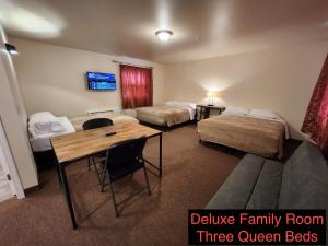 um quarto de hotel com três camas queen-size e uma mesa em Stay Inn Niagara Falls Vacation Studios em Niagara Falls