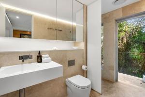 Un baño con lavabo, inodoro y espejo. en Hastings Park: Lavish Ocean Vista Luxury, en Noosa Heads 23 fotos más