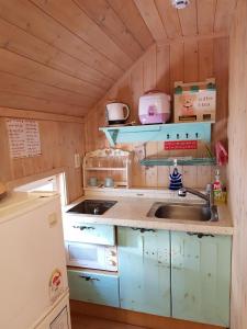una pequeña cocina con fregadero y nevera. en Finland Village Pension en Geoje 