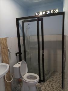 a bathroom with a shower and a toilet and a sink at Merendeng Hostel Kuta in Kuta Lombok