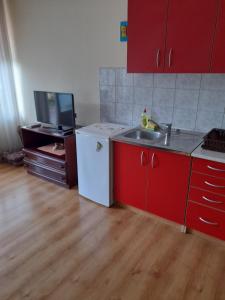 a kitchen with red cabinets and a white refrigerator at Apartment Mirjana in Banja Luka