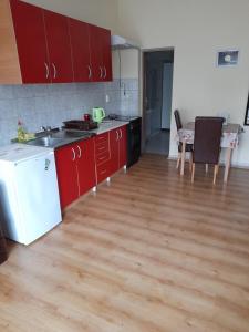a kitchen with red cabinets and a wooden floor at Apartment Mirjana in Banja Luka