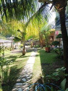 a garden with palm trees and a walk way at Merendeng Hostel Kuta in Kuta Lombok