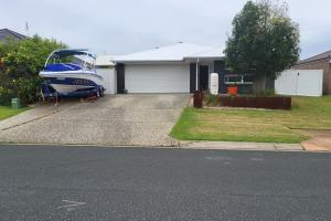 a boat parked in the driveway of a house at Sunny Coast Getaway in Bli Bli