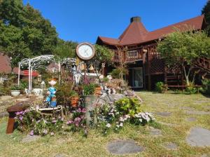 a house with a clock and flowers in front of it at Finland Village Pension in Geoje