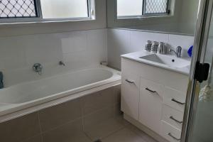 a bathroom with a white tub and a sink at Sunny Coast Getaway in Bli Bli