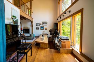 sala de estar con piano y ventana grande en 野尻湖の絶景を楽しむ、貸切サウナ付き一軒家 Anoie（あの家）, en Shinano