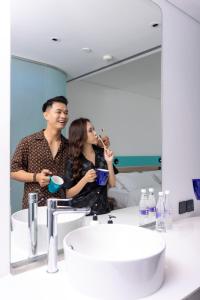 a man and a woman standing in front of a bathroom mirror at SOJO HOTEL DAK LAK in Buon Ma Thuot