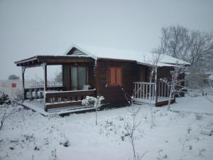 a log cabin in the snow with a porch at Orr Halevana in Bruchim Qela' Alon