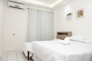 a white bedroom with two beds and a window at Apto Vista Beira Mar - Praia do Futuro a 100 mt da Praia in Fortaleza