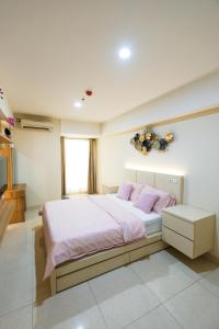 a bedroom with a bed with pink sheets and pink pillows at Warhol Residence at Louise Kienne Simpang Lima Semarang in Semarang