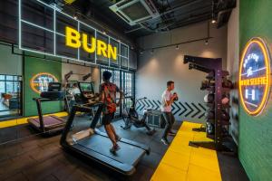 lyf Chinatown Kuala Lumpur في كوالالمبور: يمارسه رجلان على آلة ركض في صالة ألعاب رياضية