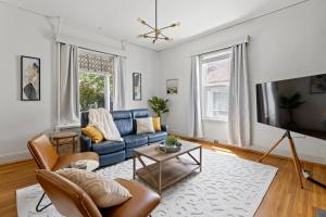 a living room with a blue couch and a tv at NEW! Modern Victorian Home in Danville