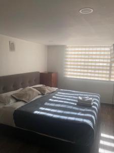 1 cama grande en un dormitorio con ventana en Apartaestudio en Bogota., en Bogotá